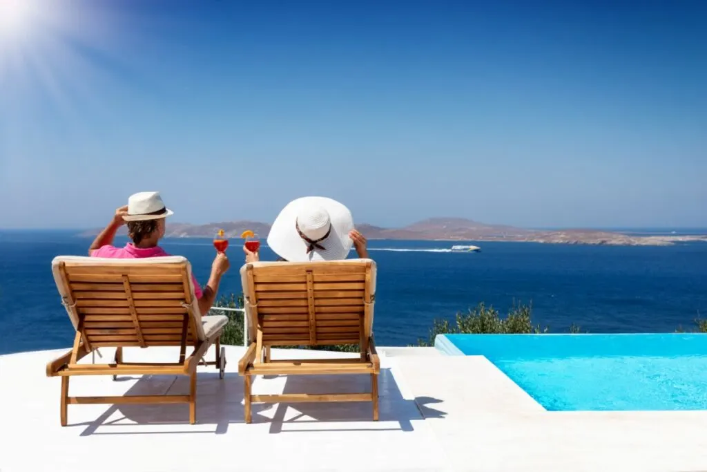 A couple drinking cocktails by the pool